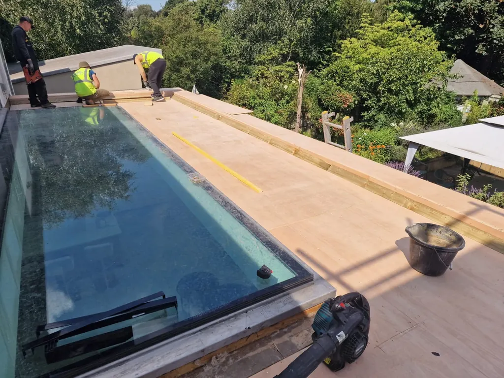 Roofers standing beside a glazed rooflight and timber decking