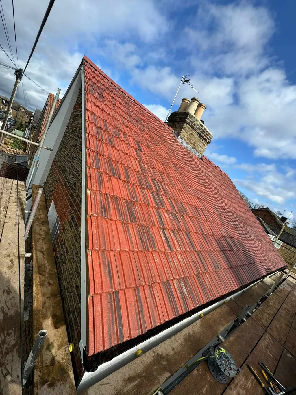 Red tiled roof slope beneath a blue and cloudy sky