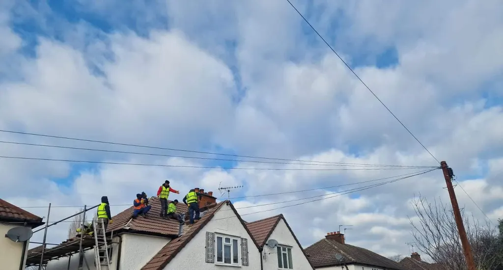 Roofers on a white gabled house beneath bright clouds